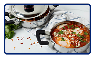 Two Royal Prestige casseroles filled with pozole ingredients near a towel and bunch of cilantro.